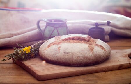 Freshly baked wheat bread on wooden cutting board. Still life with home made rustic bread.の写真素材
