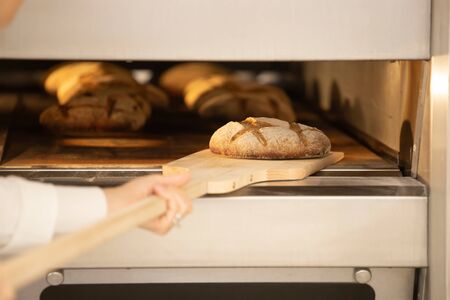 Baker bakes traditional french bread in the oven.