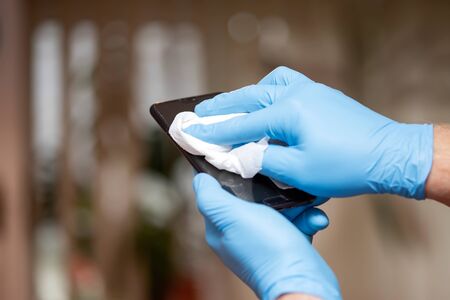 Man's  hands cleaning smartphone, spraying antibacterial sanitizing, prevent infection of...
