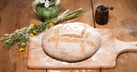 Freshly baked wheat bread on wooden cutting board. Still life with home made rustic bread.