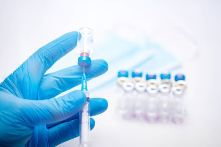 Scientist hand in blue gloves holding coronavirus, covid-19 vaccine disease, preparing for human...