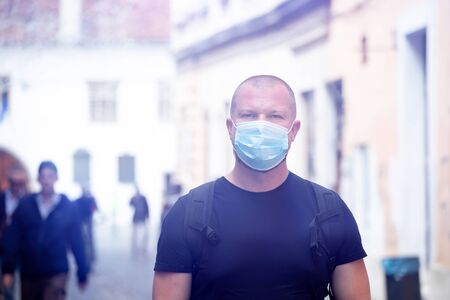 COVID-19 Pandemic Coronavirus. Man in city street wearing face mask protective for spreading of...