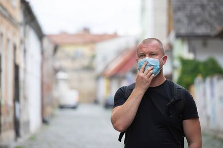 COVID-19 Pandemic Coronavirus. Man in city street wearing face mask protective for spreading of disease virus SARS-CoV-2. Man with protective mask on face against coronavirus disease.の写真素材