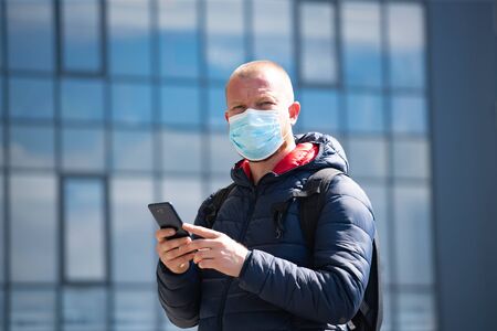 COVID-19 Pandemic Coronavirus. Tourist using the smartphone, wearing face mask protective for spreading of disease virus SARS-CoV-2.の写真素材