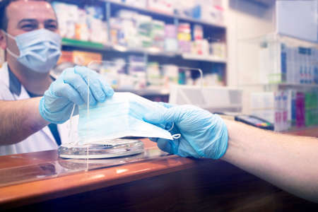 Pharmacy during Covid-19. Shopper in drugstore. People in protective medical masks buys medicine. Pharmacy, pharmacist. Covid and retailの写真素材