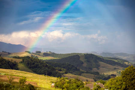 Rainbow over a green summer hills and mountains.