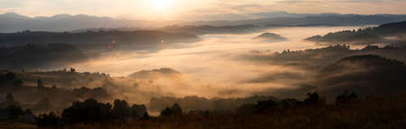 Banner of beautiful landscape in the mountains at sunrise. View of foggy hills and valley covered by...