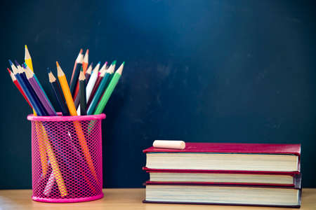 Back to School Concept. Accessories and books against chalkboard.