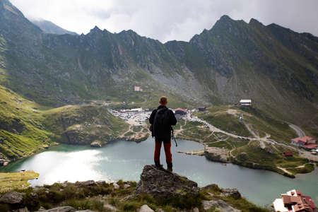 Man staying on rock peak enjoying the beautiful view of glaciar lake in the mist.の写真素材