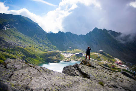 Man staying on rock peak enjoying the beautiful view of glaciar lake in the mist.