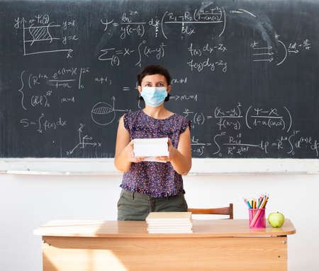 Teacher with face mask welcoming children back at school after lockdown. Back to school during COVID-19 pandemic.の写真素材
