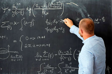 Male teacher with mask teaching math lesson at school. Social distanting and classroom safety during...