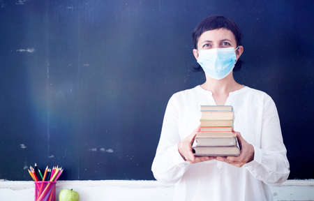 Teacher with face mask welcoming children back at school after lockdown. Back to school during COVID-19 pandemic.の写真素材