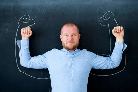 Man with muscles drawn on blackboard. Concept of power, success in business.の写真素材