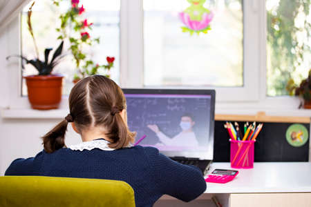 Distance learning-online education. School girl watching online education classes and doing school homework.の写真素材