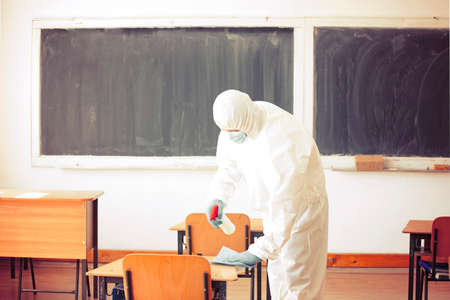 Worker sprays disinfectant as part of preventive measures against the spread of the COVID-19, the novel coronavirus in schools. Preparing for the new school season.の写真素材