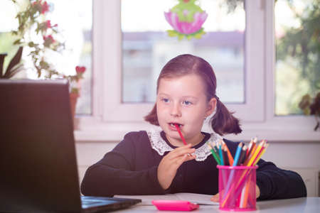 Distance learning-online education. School girl watching online education classes and doing school...
