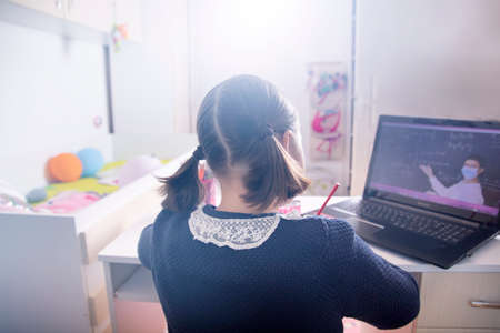 Distance learning-online education. School girl watching online education classes and doing school...