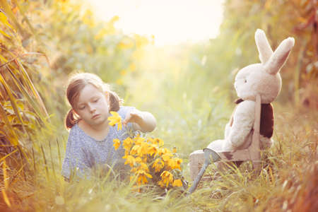 Little girl teaching her teddy in the grass. Outdoor learning concept.