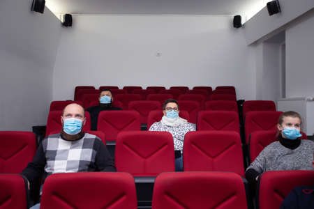 People in cinema with protection mask keeping distance away to avoid physical contact.Coronavirus COVID-19 disease protection.Social distancing practiceの写真素材