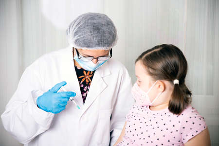 Children vaccinating immunization concept. Doctor injecting vaccination in arm of a little girl with...
