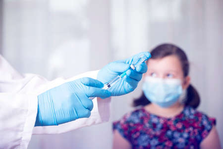 Children vaccinating immunization concept. Doctor injecting vaccination in arm of a little girl with...