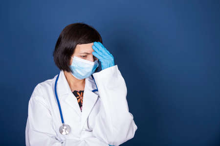 Stressed, tired doctor during COVID-19 needing help in hospital. Healthcare workers in despair over emergency. Coronavirus crisis death, dispair, mental health anxiety.の写真素材