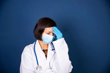 Stressed, tired doctor during COVID-19 needing help in hospital. Healthcare workers in despair over emergency. Coronavirus crisis death, dispair, mental health anxiety.の写真素材