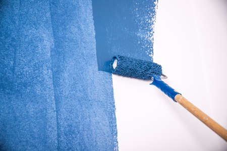Paintign the wall in blue with roller brush.の写真素材