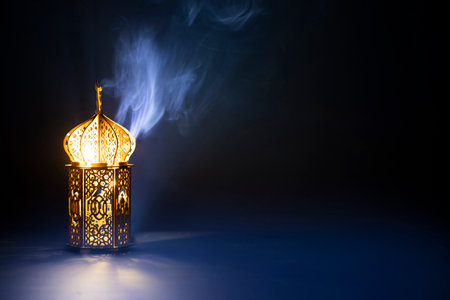 Ornamental Arabic lantern with burning candle glowing at night and glittering golden bokeh lights. Festive greeting card for Muslim holy month Ramadan Kareem.の写真素材