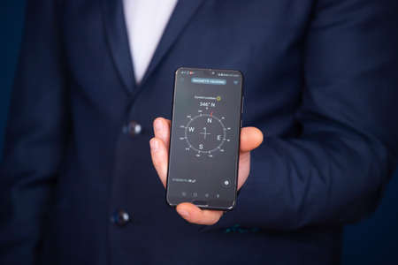 Businessman holding a smartphone with navigation compass. Business planning and strategy growth,...