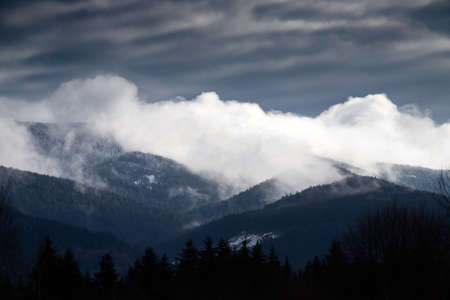 Mountain range with visible silhouettes through the morning colorful fog.の写真素材