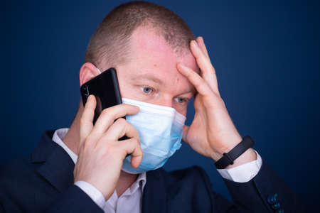 Businessman wearing medical mask talking on the phone in the office.