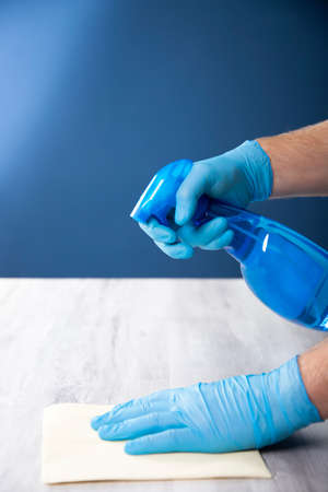 Sanitize surfaces prevention in hospitals and public spaces. Surface home cleaning spraying antibacterial sanitizing spray bottle. disinfecting against COVID-19 spreading, wearing medical blue gloves.の写真素材