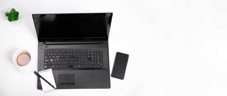 Office stuff with smartphone, laptop and coffee cup - top view shot.