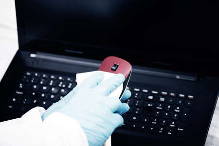 Office sanitizing wiping mouse with disinfectant. Coronavirus COVID-19 sanitize cleaning, disinfection of work desk.の写真素材