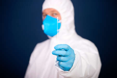 Medical healthcare holding COVID-19, coronavirus swab collection kit, wearing protective suitの写真素材