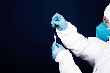Medical healthcare holding COVID-19, coronavirus swab collection kit, wearing protective suit
