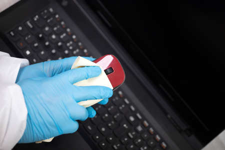 Office sanitizing wiping mouse with disinfectant. Coronavirus COVID-19 sanitize cleaning, disinfection of work desk.の写真素材