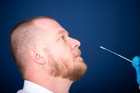 Medical staff member with protective equipment performs Coronavirus nasal swabs to patient. Laboratory tests for coronavirus concept.の写真素材