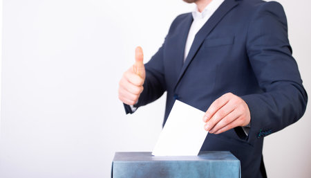 Hand of a voter putting vote in the ballot box. Election concept.の写真素材