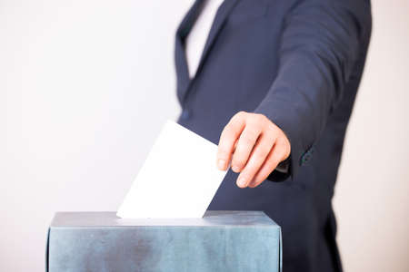 Hand of a voter putting vote in the ballot box. Election concept.