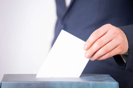 Hand of a voter putting vote in the ballot box. Election concept.の写真素材
