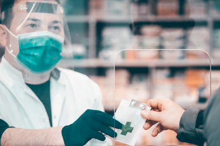 Pharmacy during Covid-19. Shopper in drugstore. People in protective medical masks buys medicine. Pharmacy, pharmacist. Covid and retailの写真素材