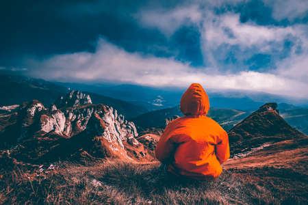 Woman sitting on cliff enjoying mountains landscape. Lifestyle concept. Traveling active adventure vacations.の写真素材