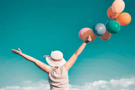 Young woman with colorful balloons in summer field - retro styled photo