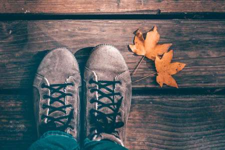 Autumn background of woman shoes over wooden background with autumn leaves.の写真素材