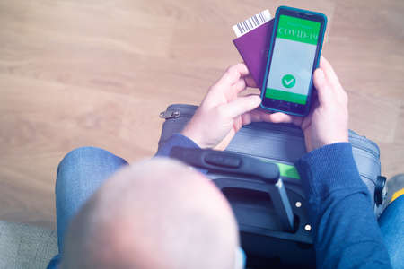 Vaccinated person using digital health passport app in mobile phone for travel during covid-19...