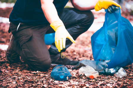 Hand picking up garbage plastic for cleaning the woods or parks. Environmental protection, Earth...