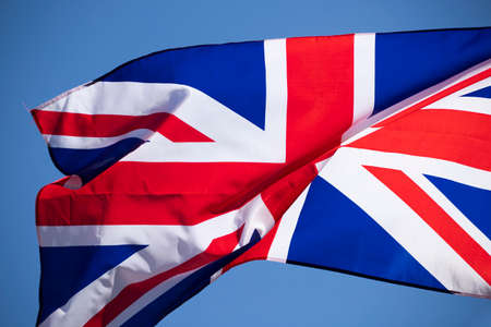 Waving union jack flag on blue sky.の写真素材